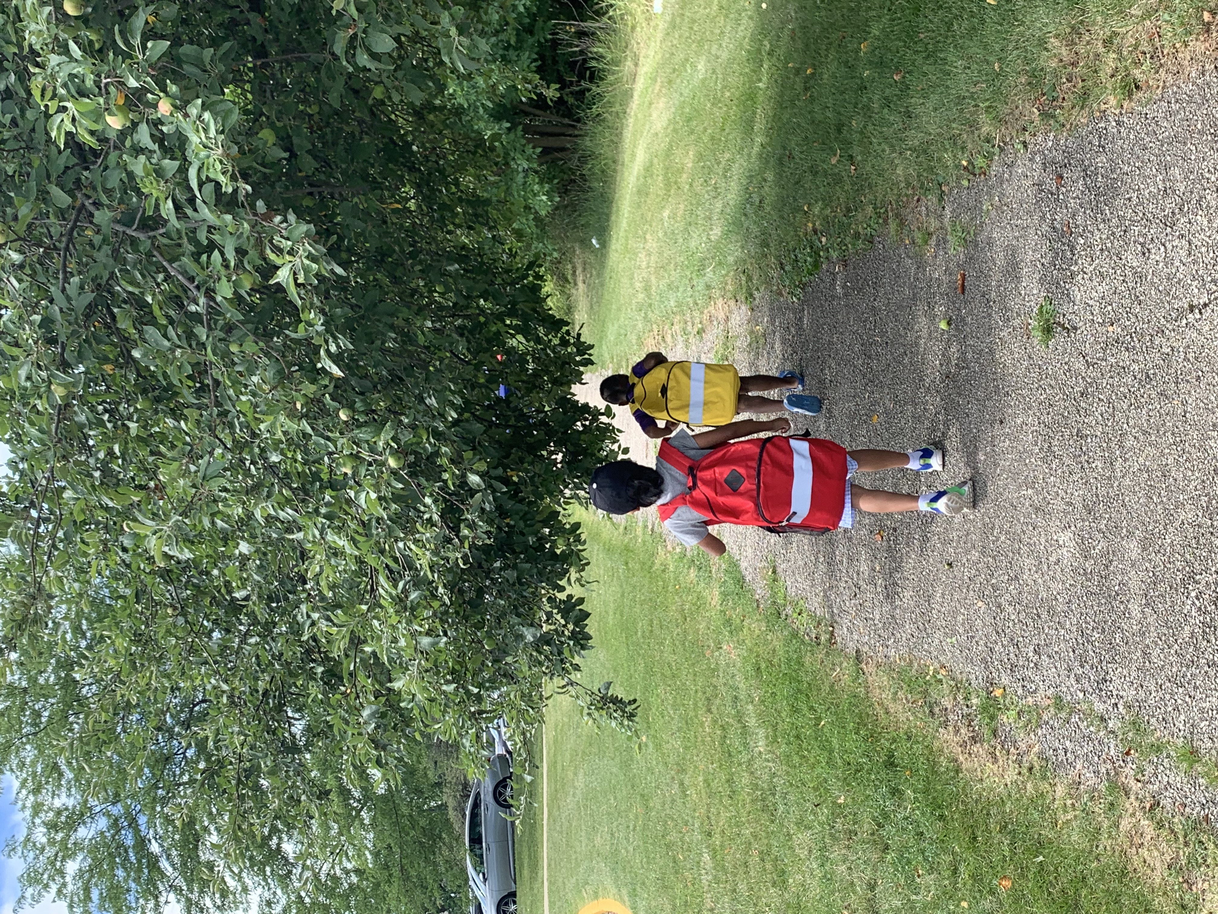 A child with a large backpack walks down a trail