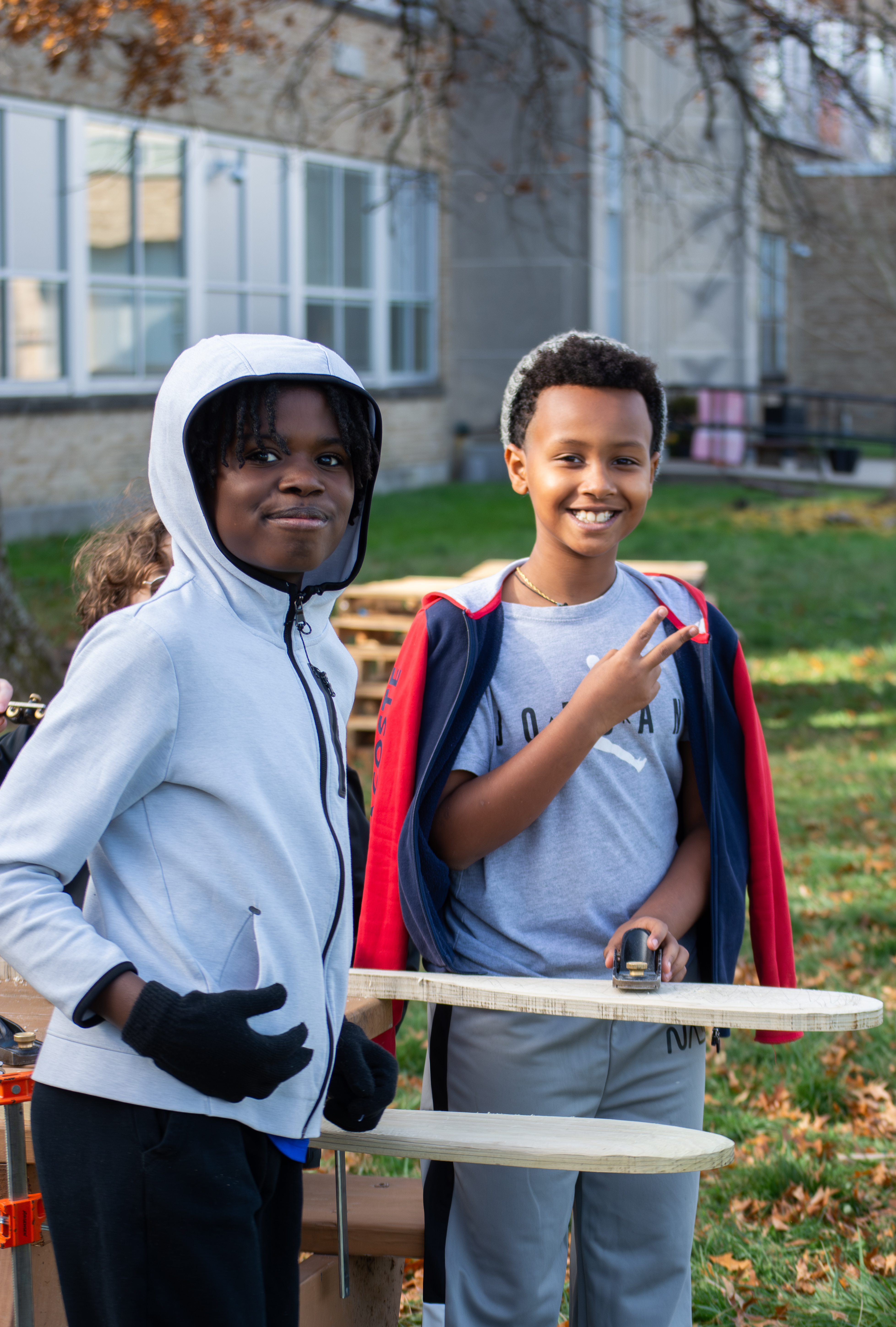 Two kids smile while holding tools