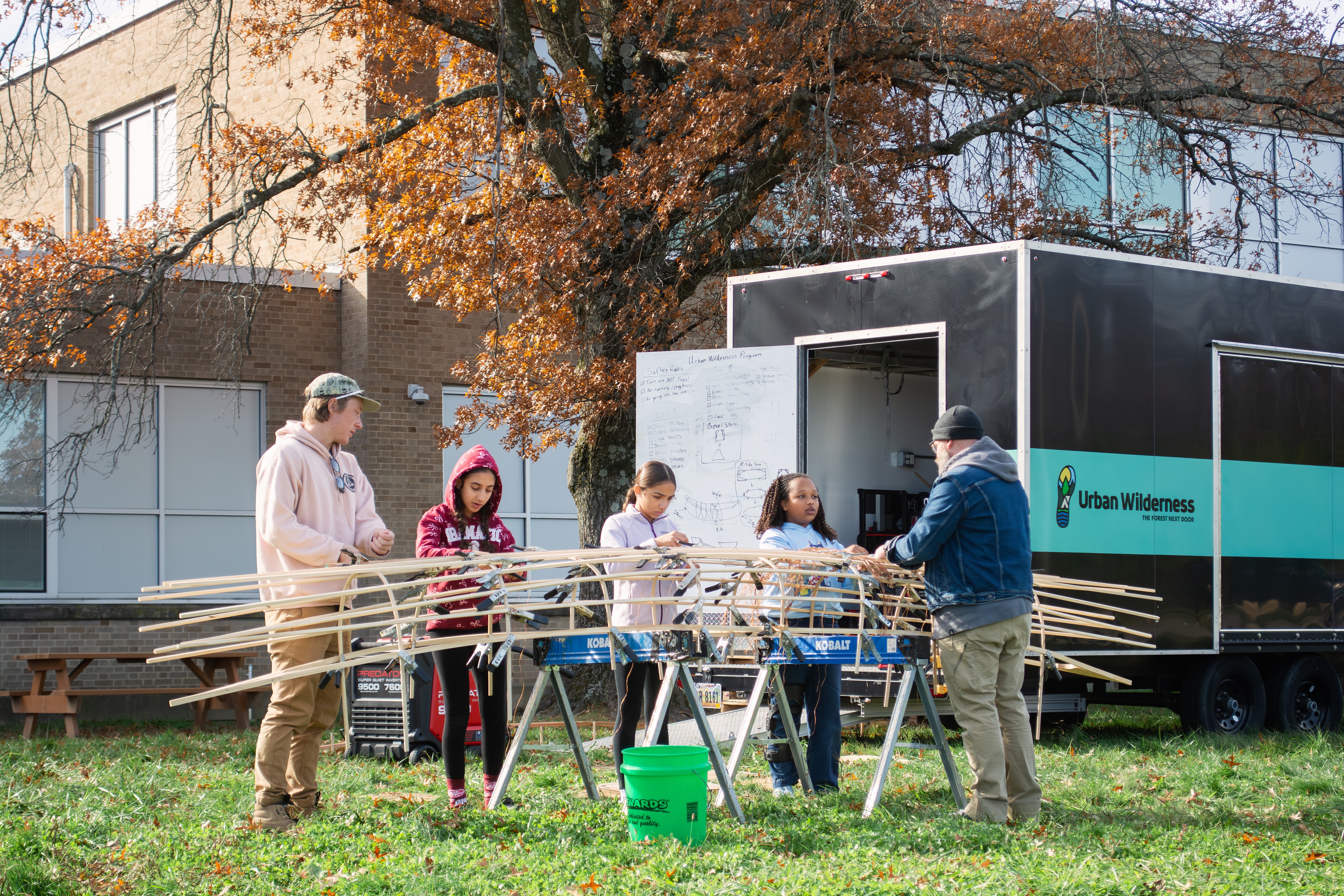 a group of kids build a canoe outdoors