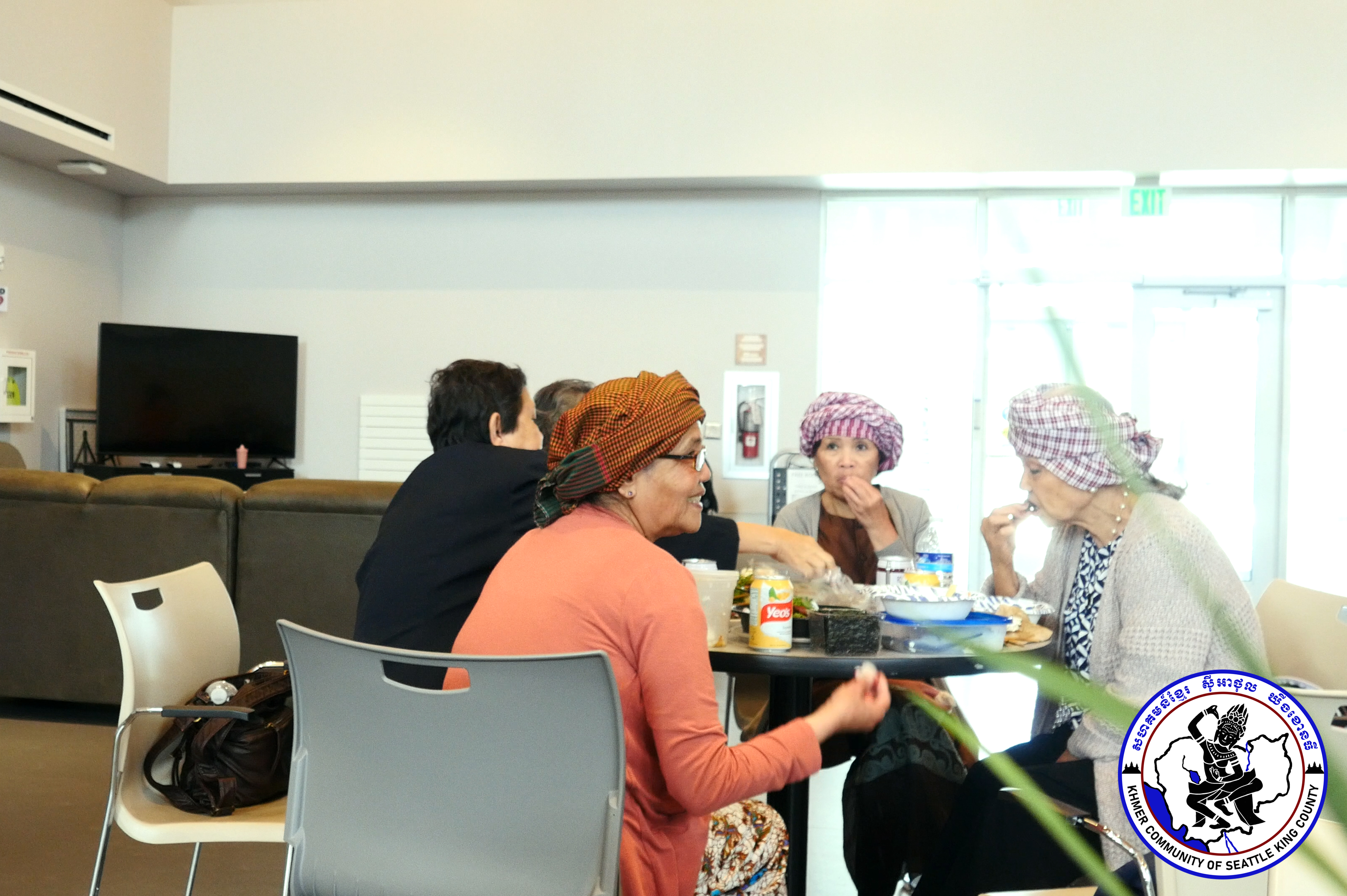 Elders sit around a table and share food