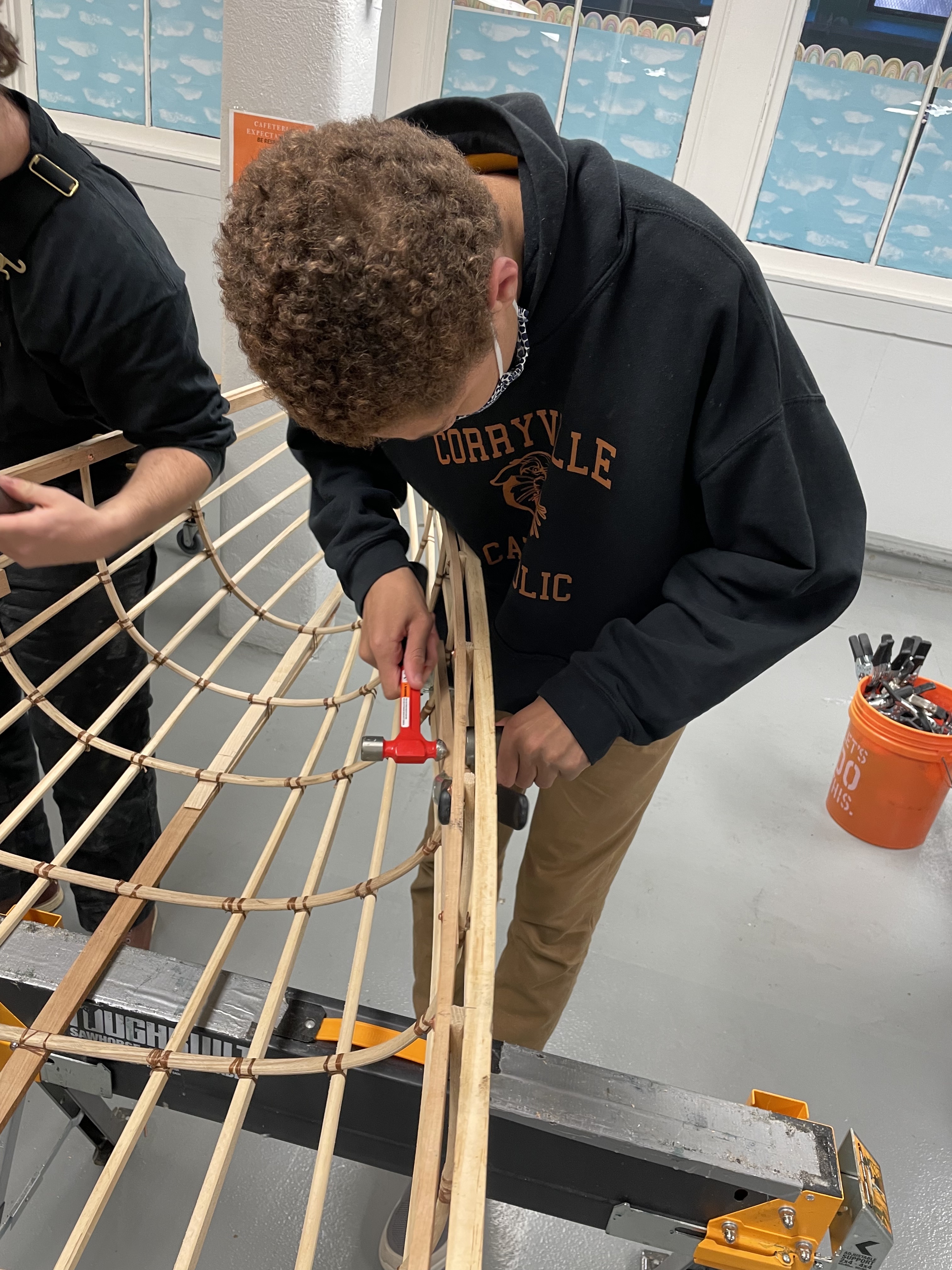 A student leans over the shell of a canoe
