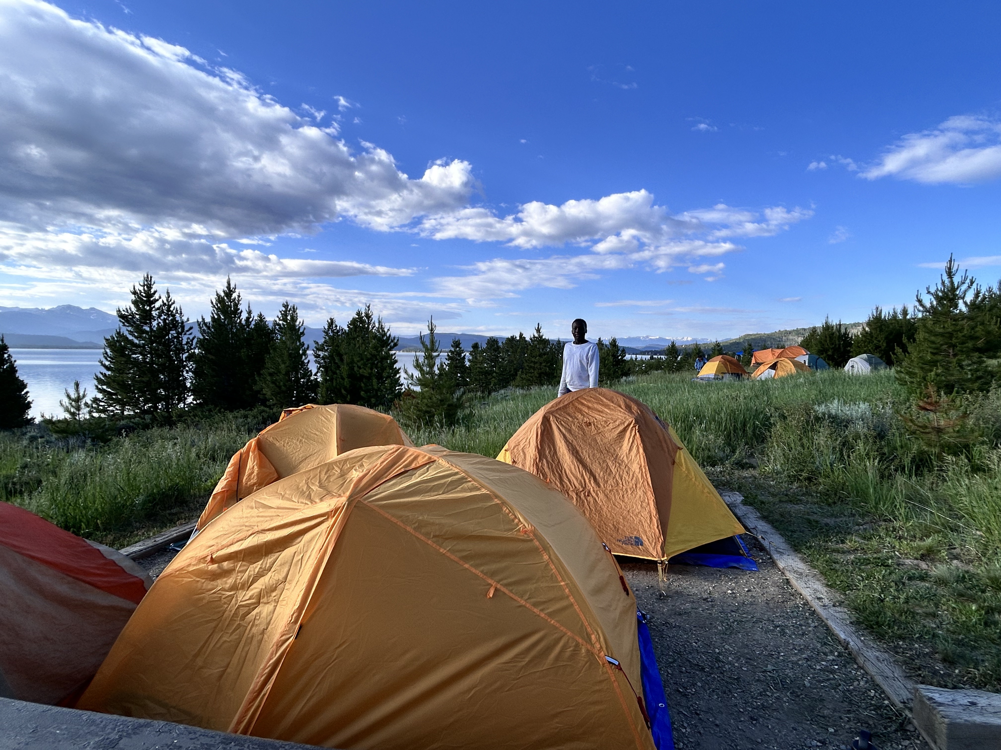 A teenager stands near a cluster of tents