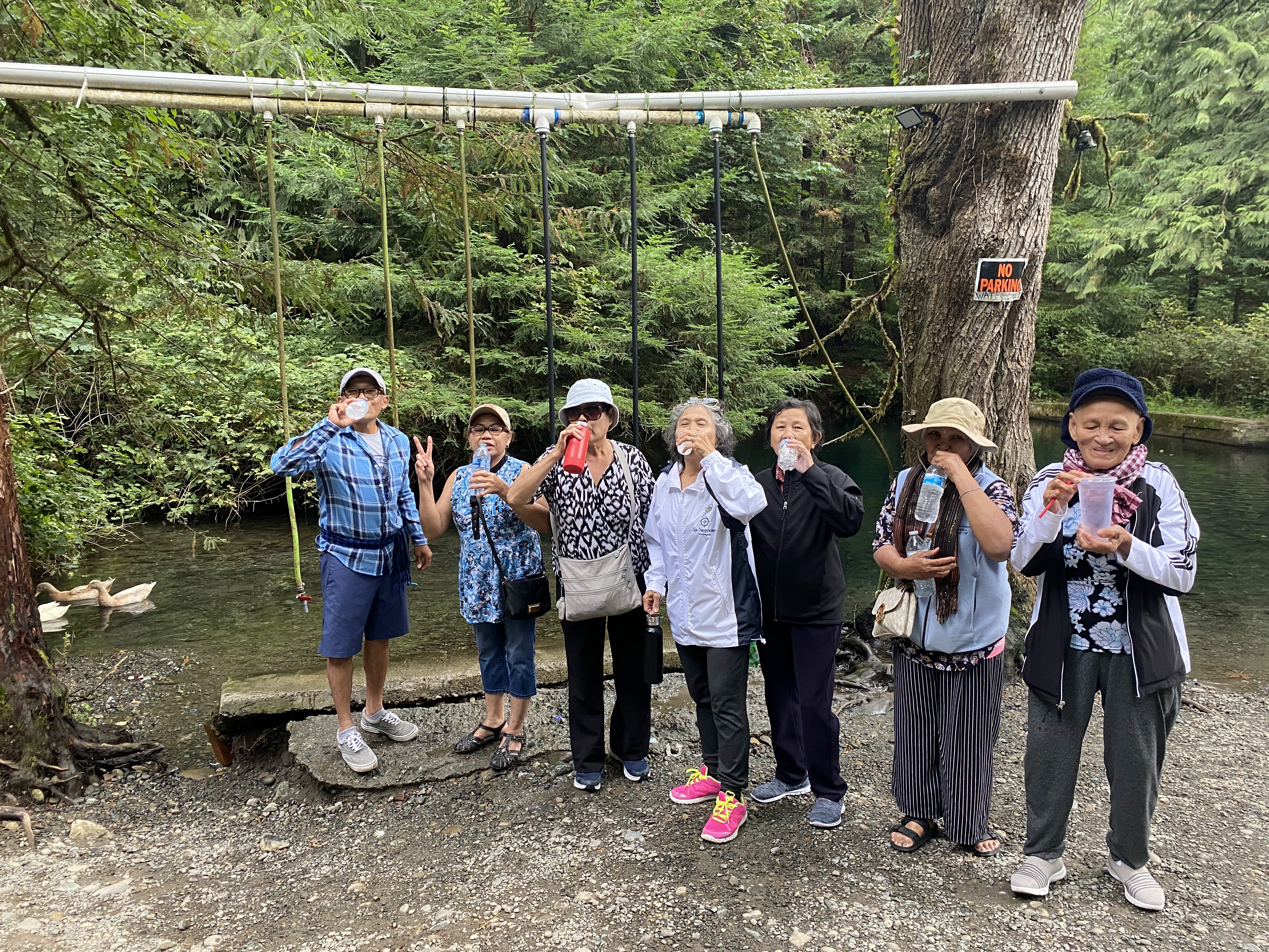 Elders stand by a creek and smile