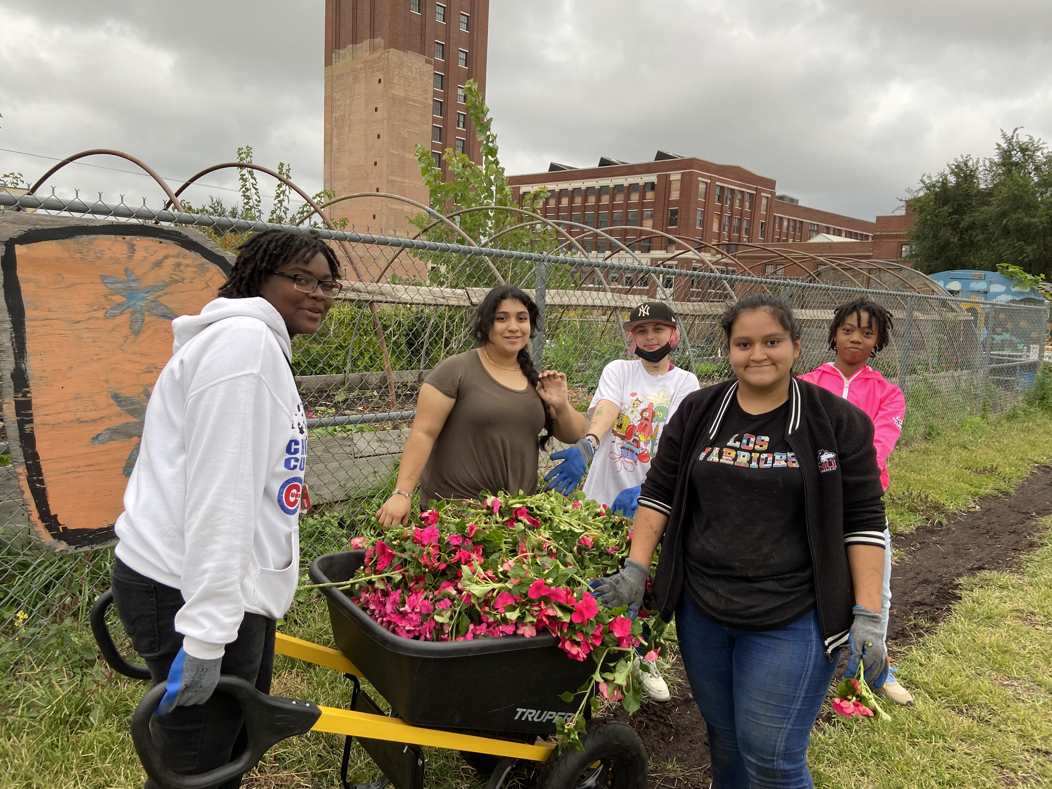Students gather around a wheelbarrow in a garden