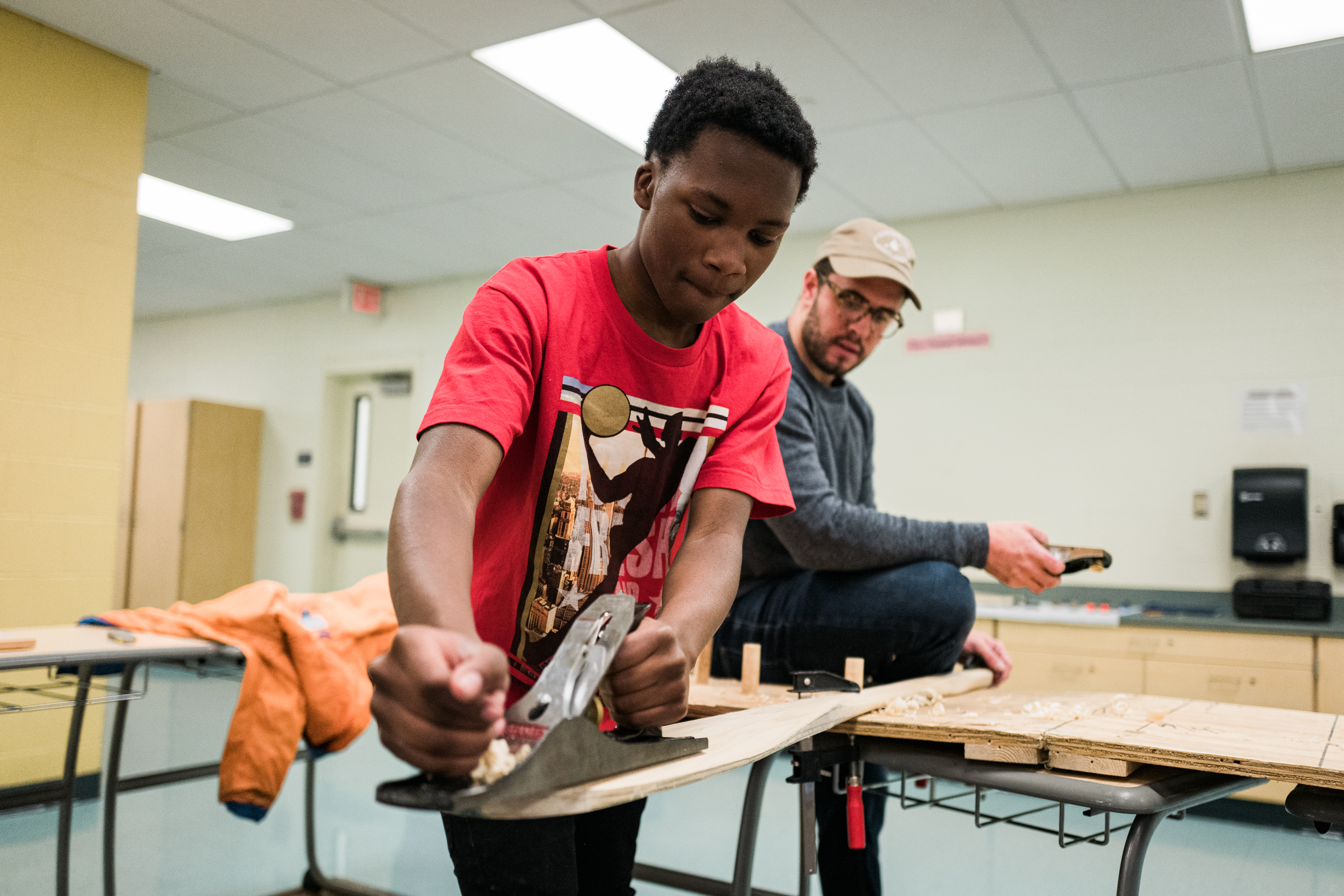 a young man uses tools to hand build a boat