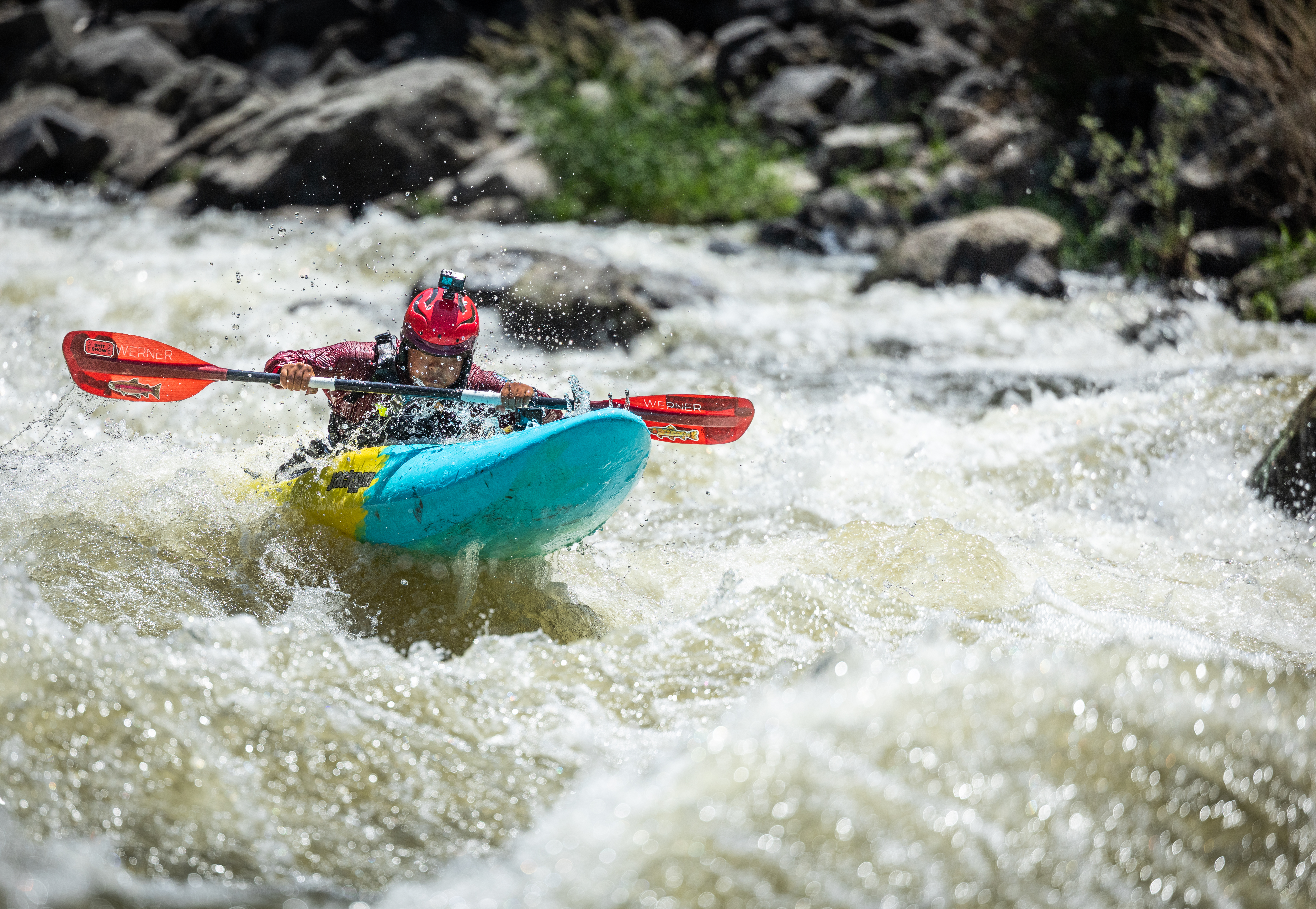a young person kayaks solo through whitewater