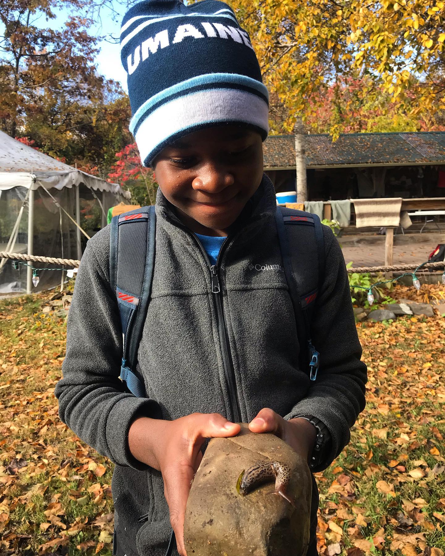 a young boy holds a rock with a slug on it