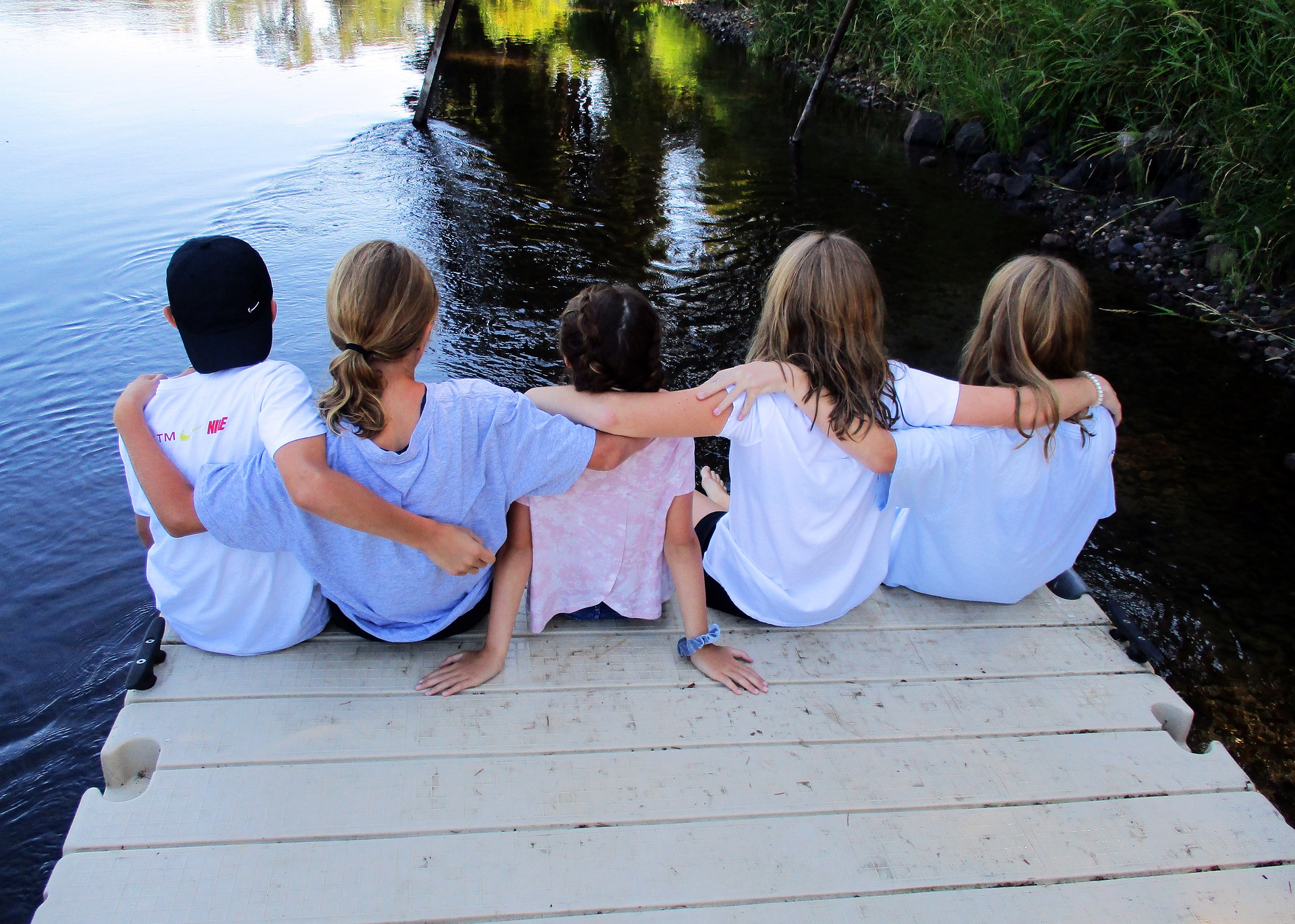 a group of campers sits on the edge of a dock