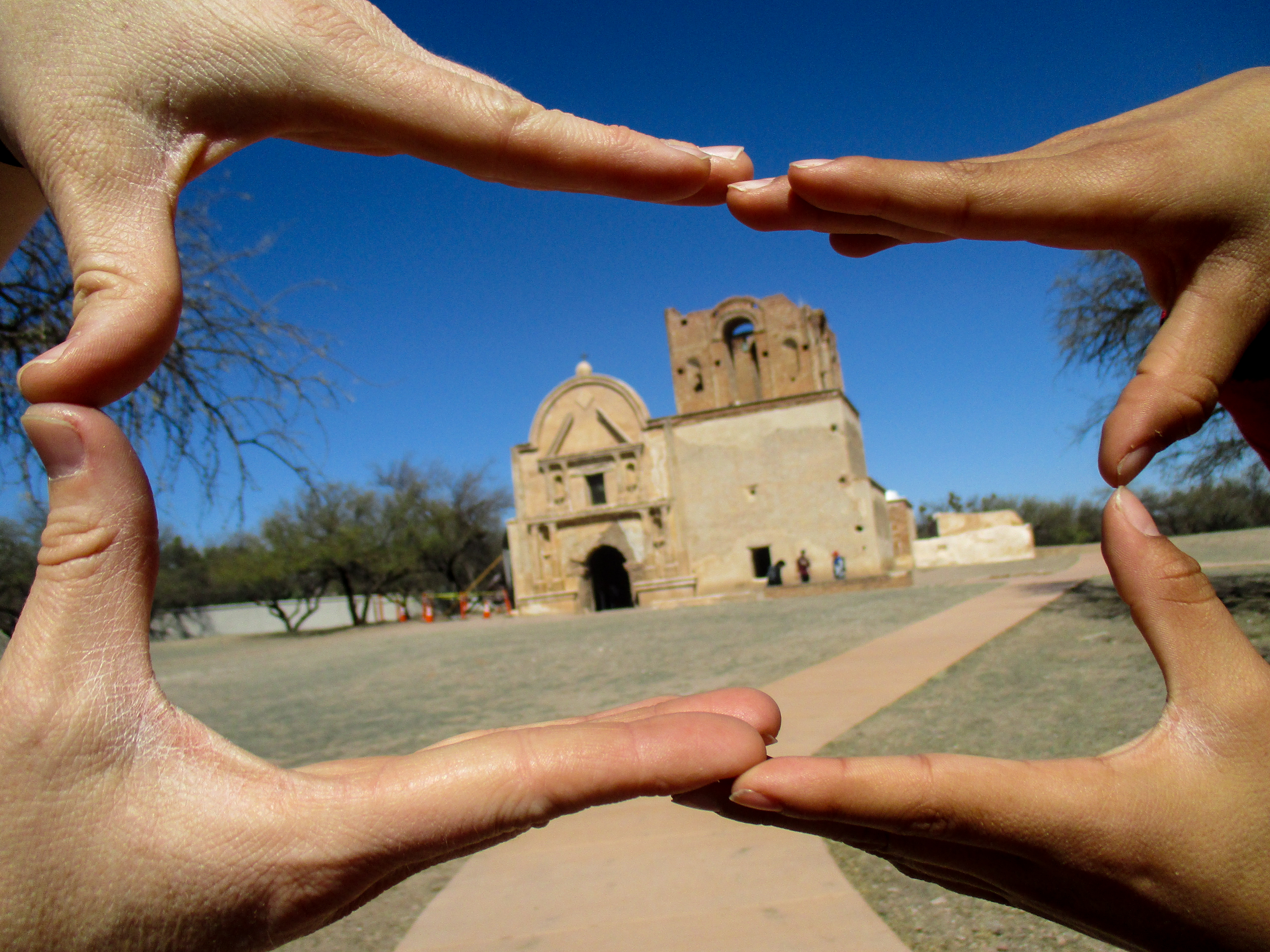 four hands form a frame around a building in the distance