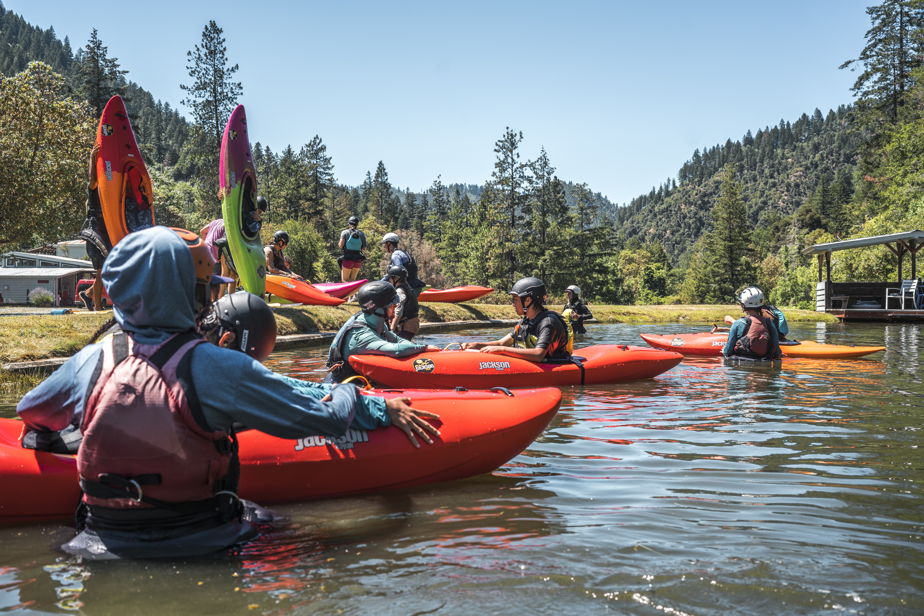 People stand in a river holding kayaks